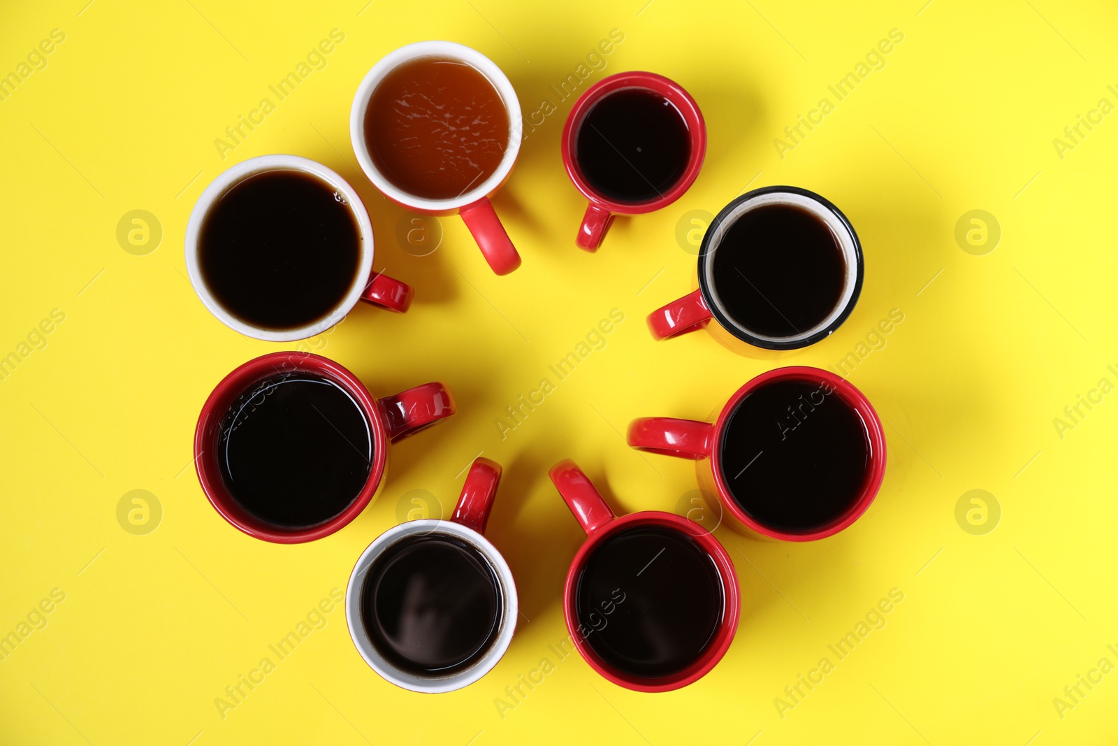 Different cups with aromatic coffee drinks on yellow background, flat lay Photo of Different cups with aromatic coffee drinks on yellow background, flat lay