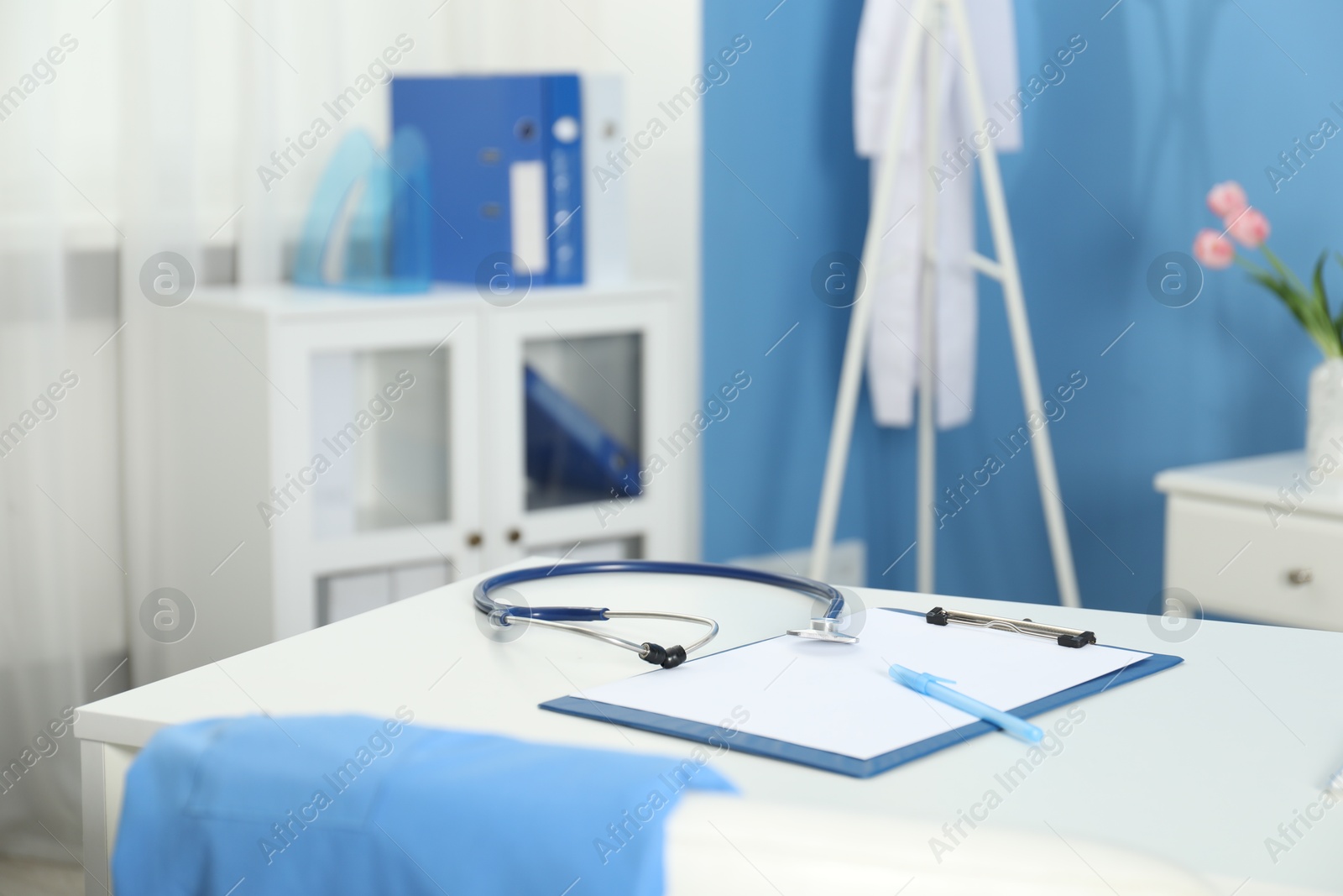 Doctor's workplace. Stethoscope, clipboard and pen on white table in medical office Photo of Doctor's workplace. Stethoscope, clipboard and pen on white table in medical office