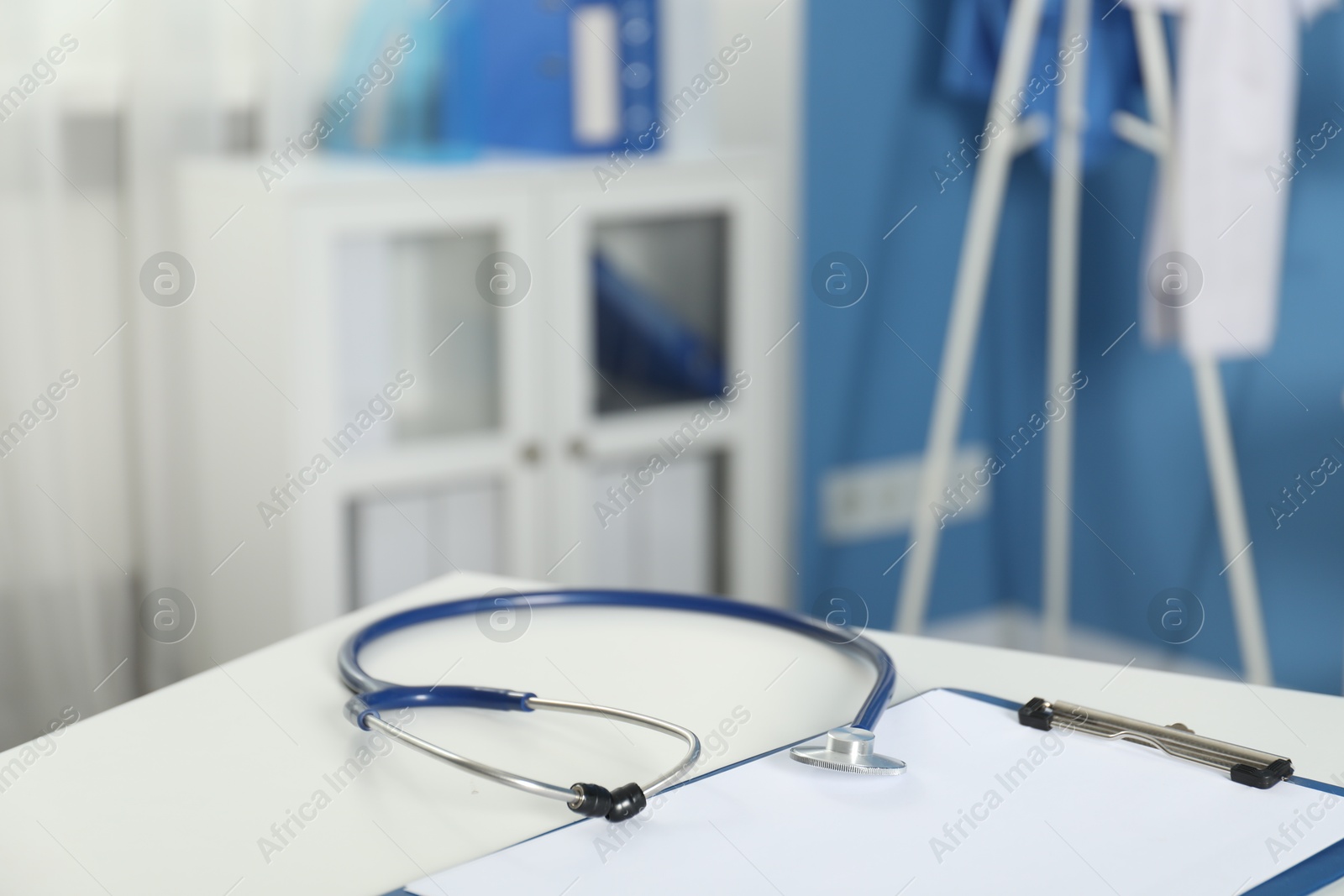 Doctor's workplace. Stethoscope and clipboard on white table in medical office, closeup. Space for text Photo of Doctor's workplace. Stethoscope and clipboard on white table in medical office, closeup. Space for text