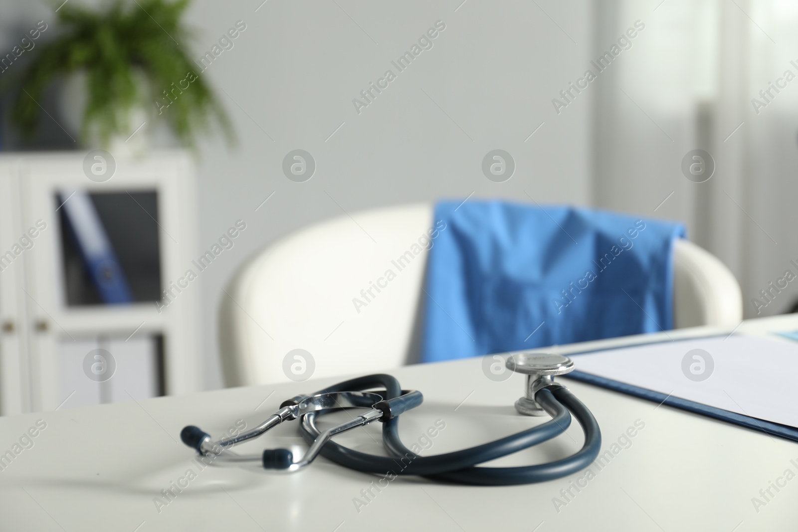 Doctor's workplace. Stethoscope and clipboard on white table in medical office, closeup. Space for text Photo of Doctor's workplace. Stethoscope and clipboard on white table in medical office, closeup. Space for text