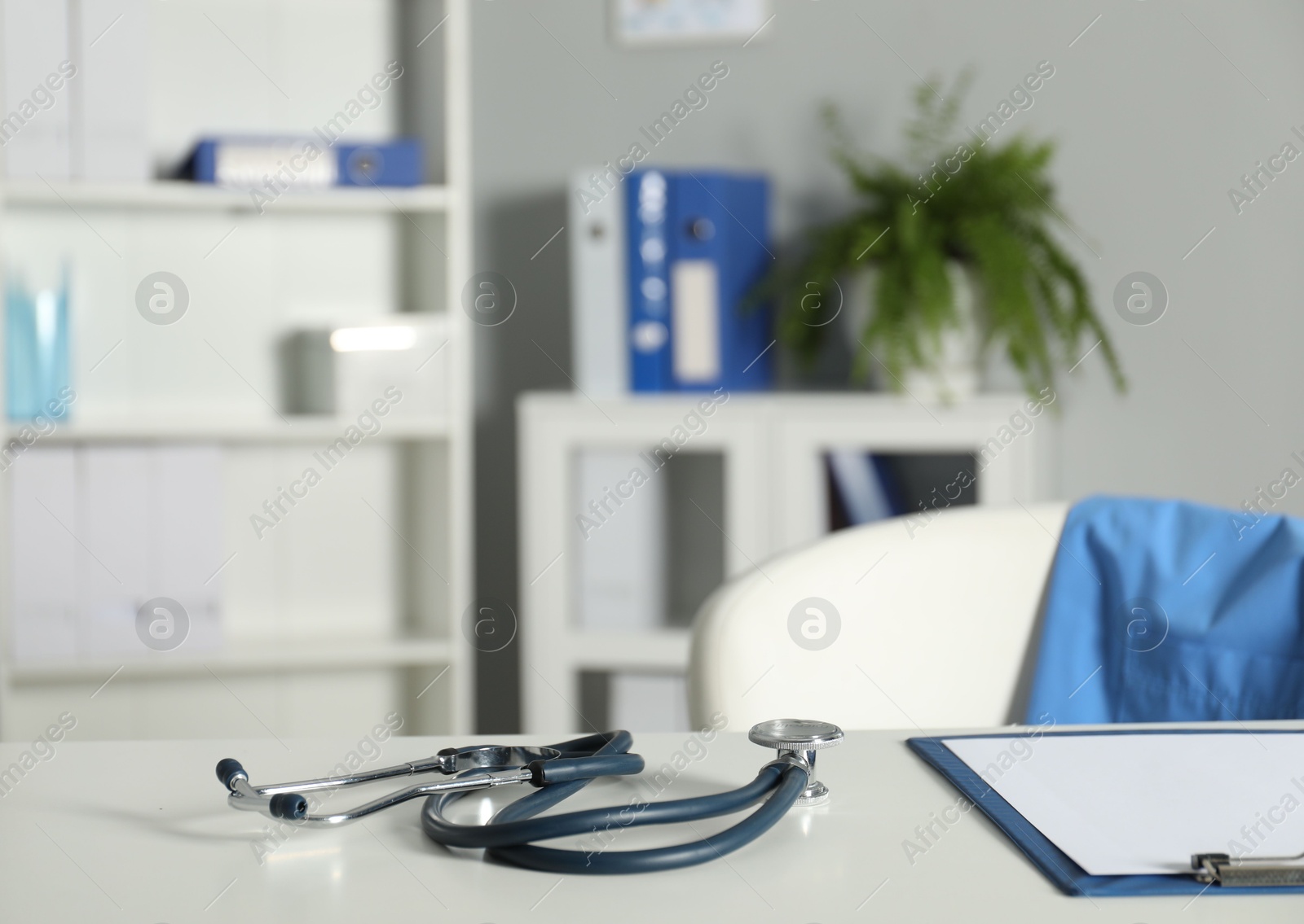 Doctor's workplace. Stethoscope and clipboard on white table in medical office, closeup. Space for text Photo of Doctor's workplace. Stethoscope and clipboard on white table in medical office, closeup. Space for text