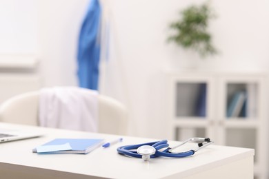 Photo of Doctor's workplace. Stethoscope and stationery on white table in medical office, space for text