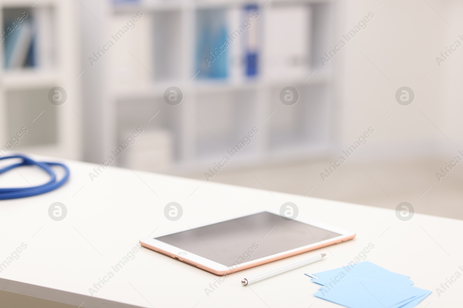 Doctor's workplace. Tablet, pen and sticky notes on white table in medical office, closeup. Space for text Photo of Doctor's workplace. Tablet, pen and sticky notes on white table in medical office, closeup. Space for text