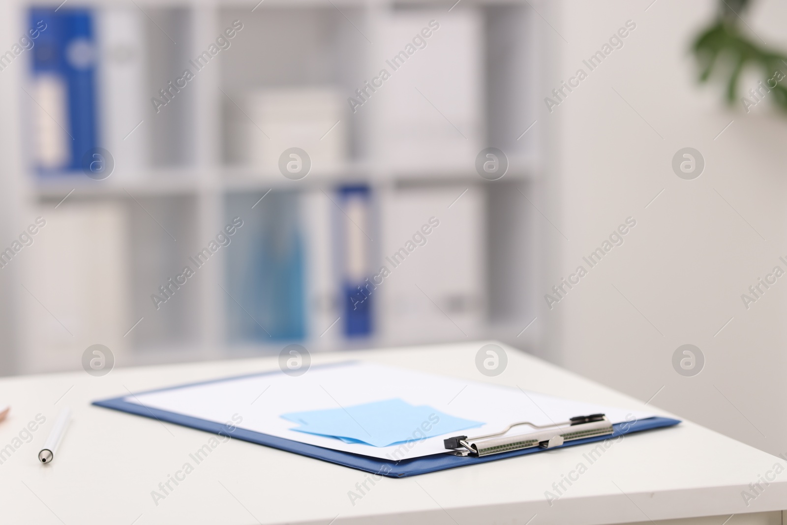 Doctor's workplace. Clipboard and sticky notes on white table in medical office, closeup. Space for text Photo of Doctor's workplace. Clipboard and sticky notes on white table in medical office, closeup. Space for text