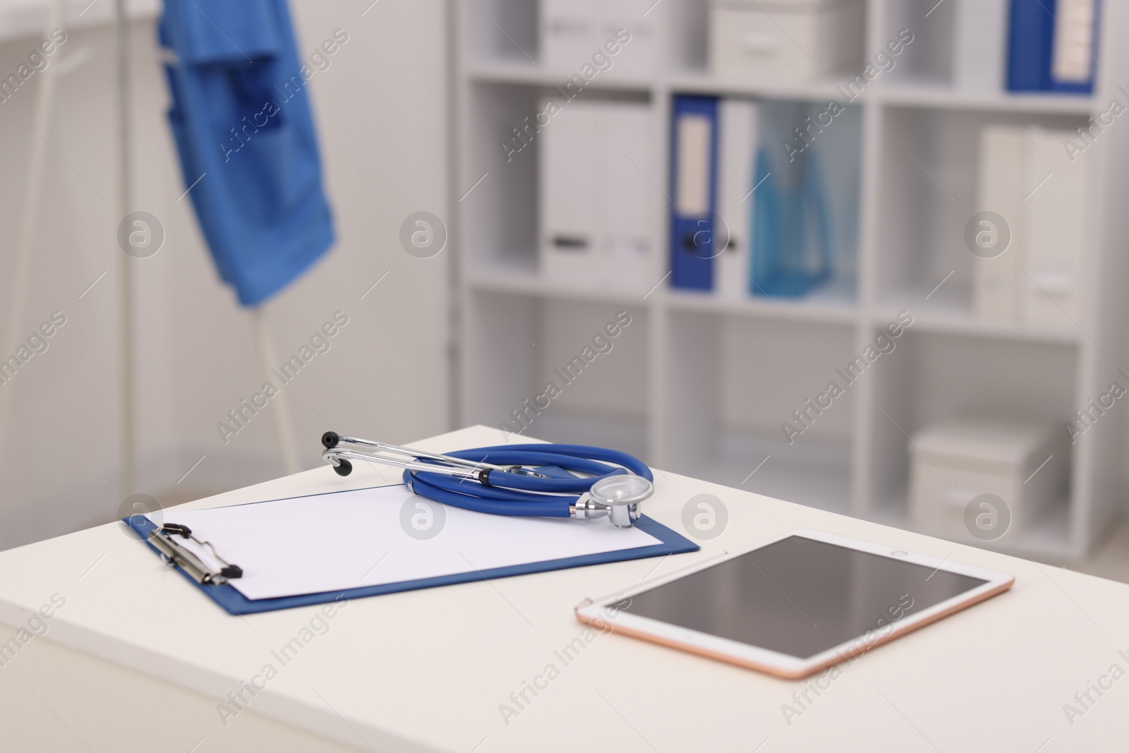 Doctor's workplace. Tablet, clipboard and stethoscope on white table in medical office Photo of Doctor's workplace. Tablet, clipboard and stethoscope on white table in medical office