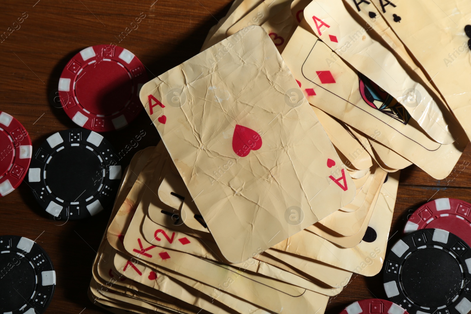 Photo of Many old vintage playing cards and poker chips on wooden table, flat lay