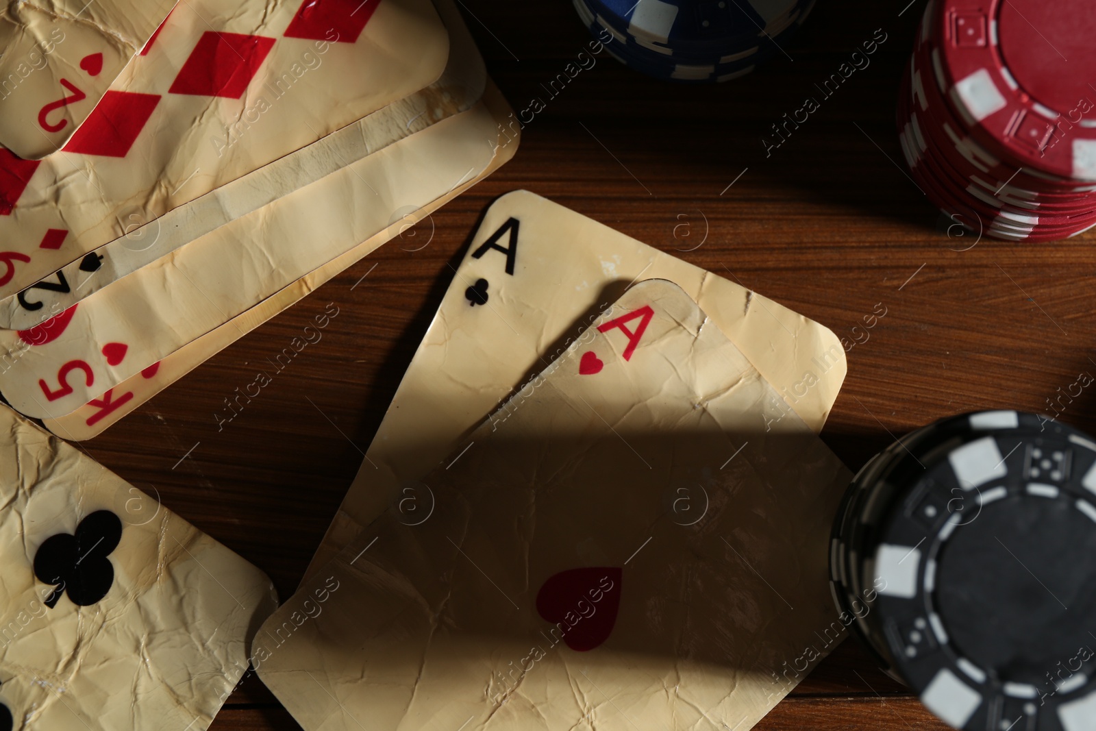 Old vintage playing cards and poker chips on wooden table, flat lay Photo of Old vintage playing cards and poker chips on wooden table, flat lay