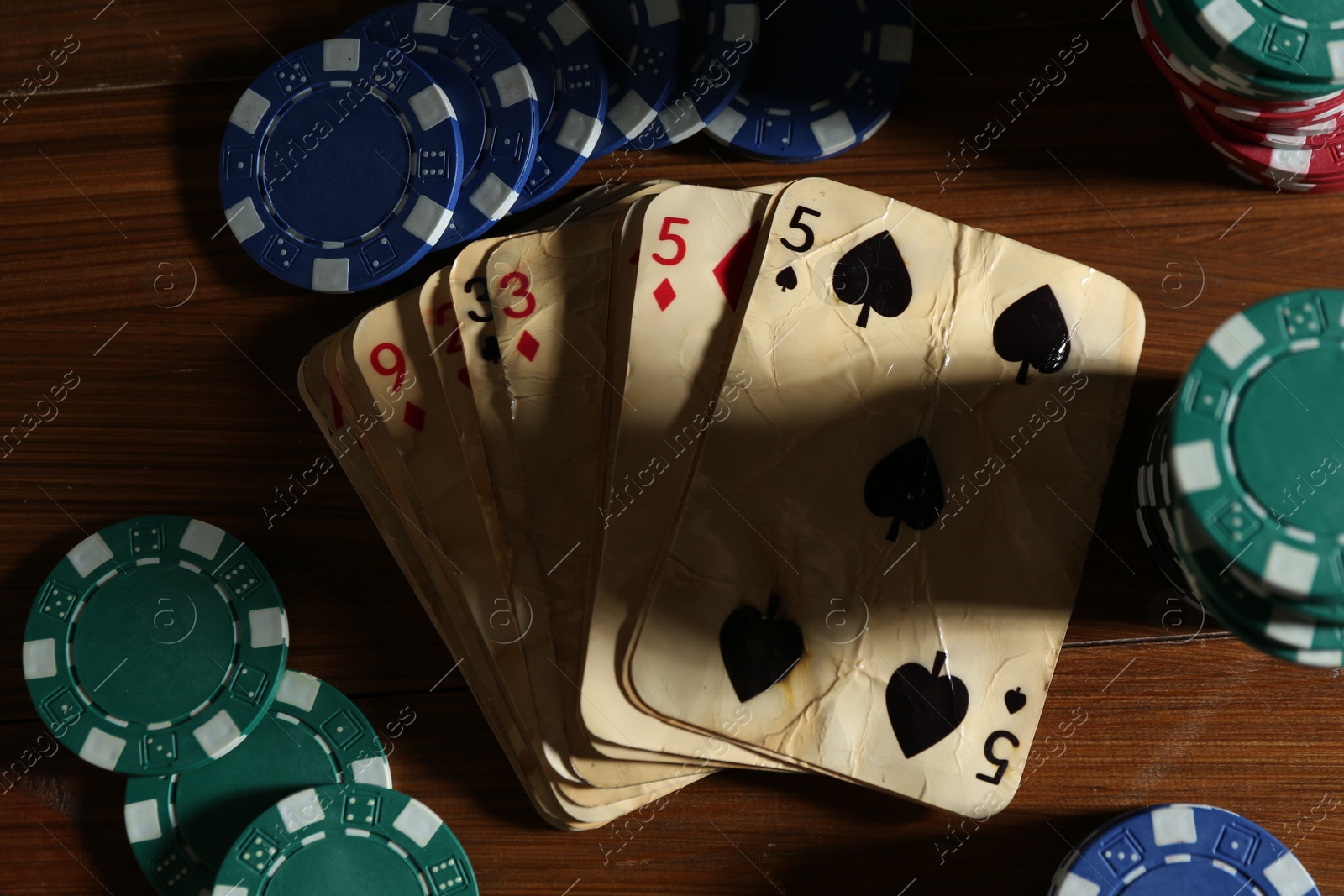 Old vintage playing cards and poker chips on wooden table, flat lay Photo of Old vintage playing cards and poker chips on wooden table, flat lay