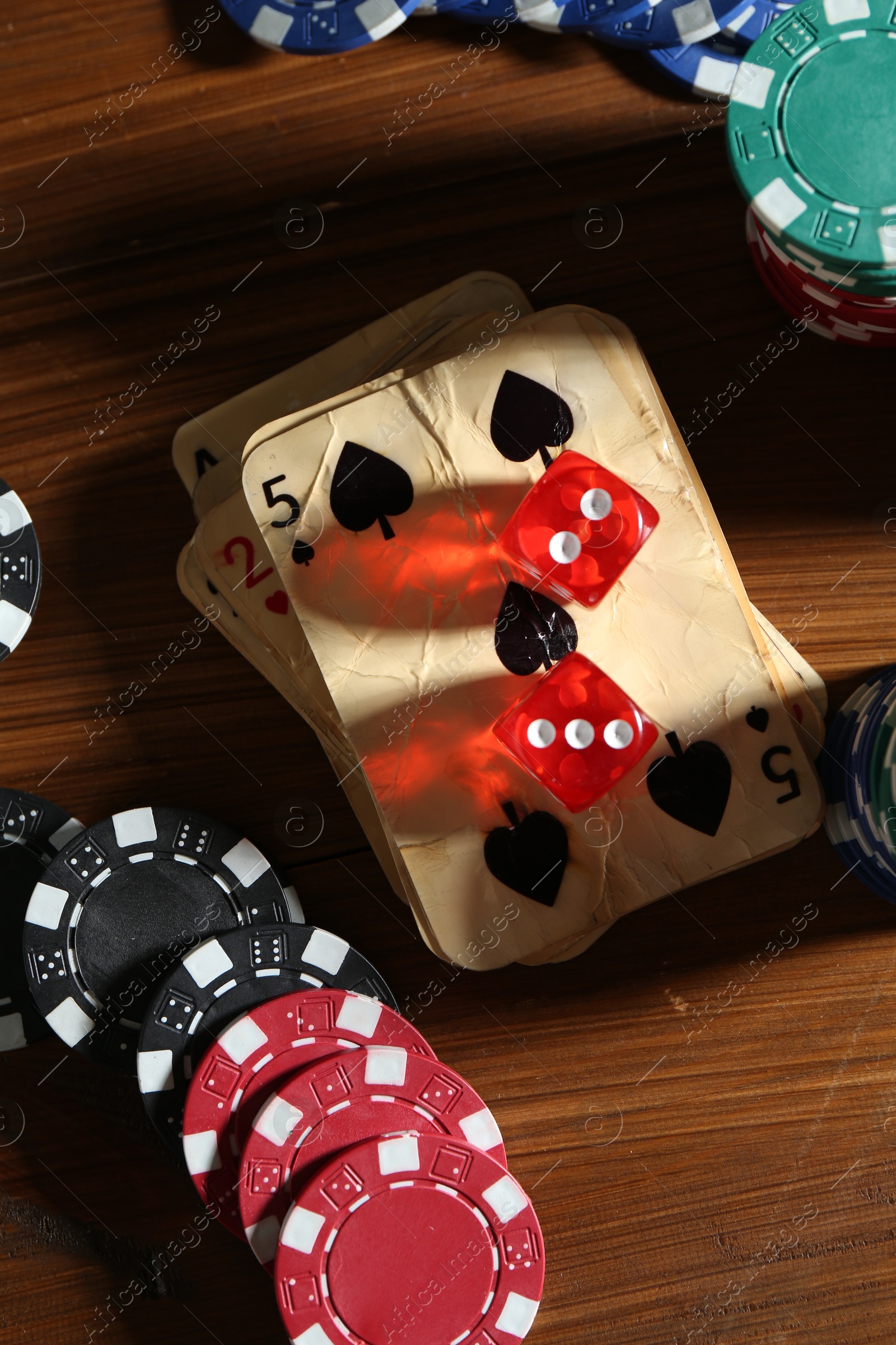 Old vintage playing cards, poker chips and dices on wooden table, flat lay Photo of Old vintage playing cards, poker chips and dices on wooden table, flat lay