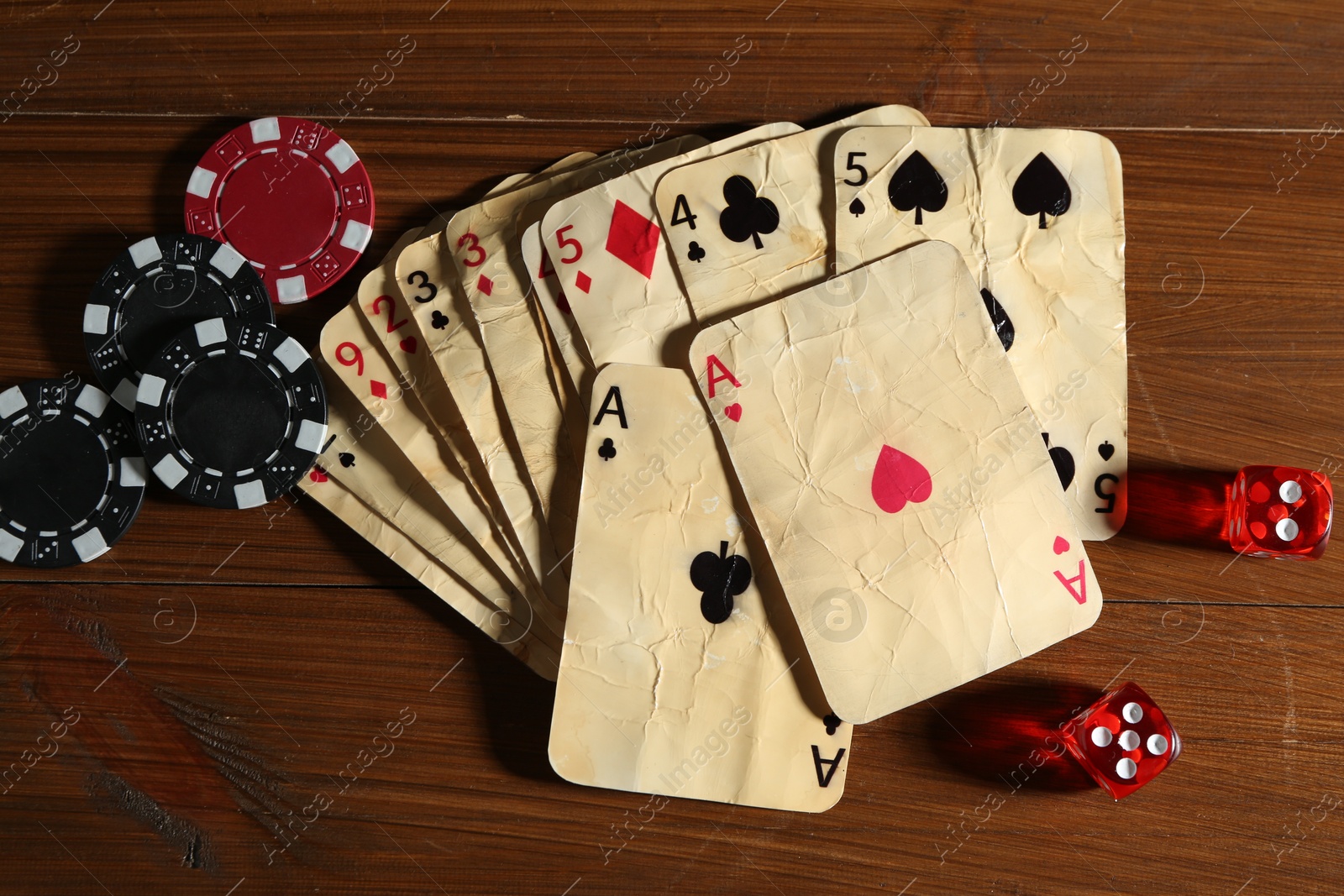 Old vintage playing cards, poker chips and dices on wooden table, flat lay Photo of Old vintage playing cards, poker chips and dices on wooden table, flat lay