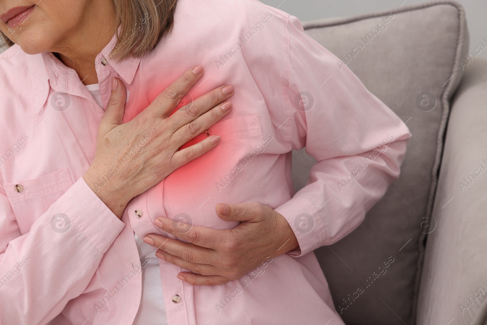 Heart attack. Senior woman suffering from pain in chest on sofa at home, closeup Image of Heart attack. Senior woman suffering from pain in chest on sofa at home, closeup