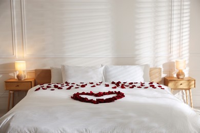 Photo of Heart made with rose petals on bed indoors