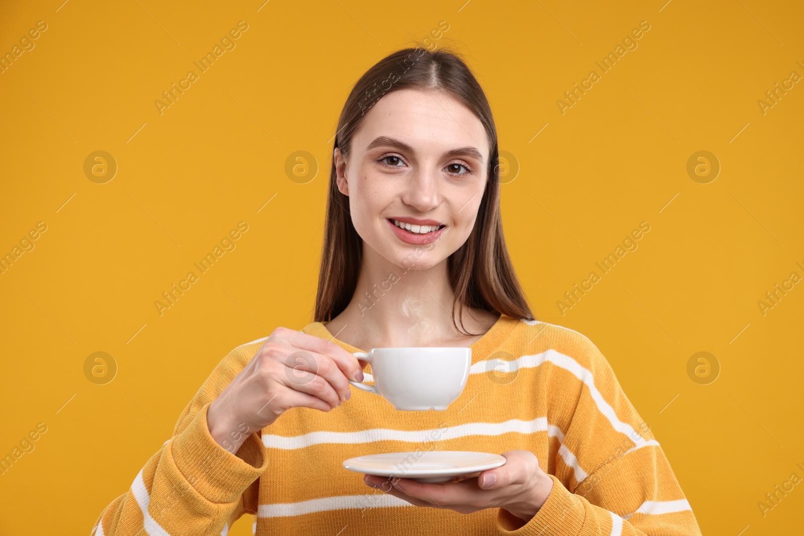 Smiling woman with cup of coffee on yellow background Photo of Smiling woman with cup of coffee on yellow background