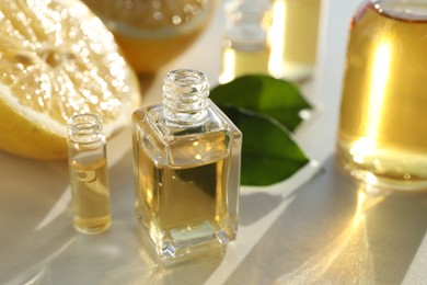 Photo of Perfume bottles with aromatic oils and lemons on light background, closeup