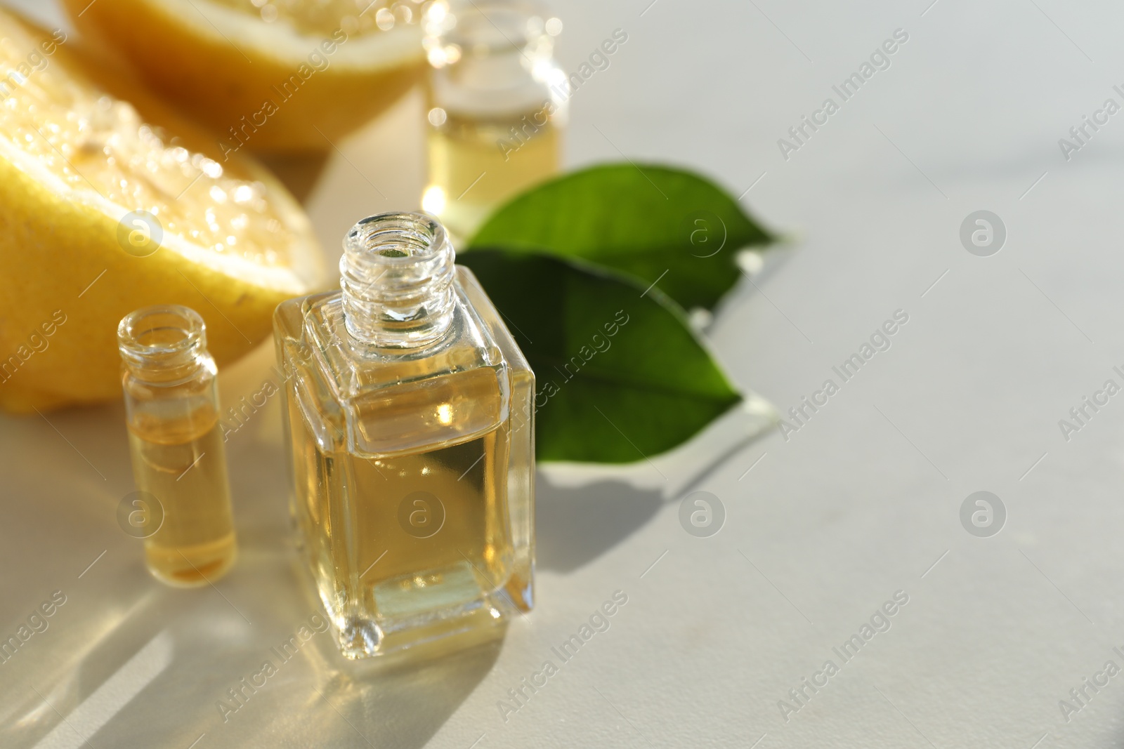 Perfume bottles with aromatic oils and lemons on light background, closeup. Space for text Photo of Perfume bottles with aromatic oils and lemons on light background, closeup. Space for text