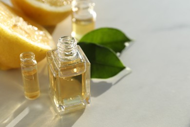 Photo of Perfume bottles with aromatic oils and lemons on light background, closeup. Space for text