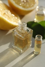 Photo of Perfume bottles with aromatic oils and lemons on light background, closeup