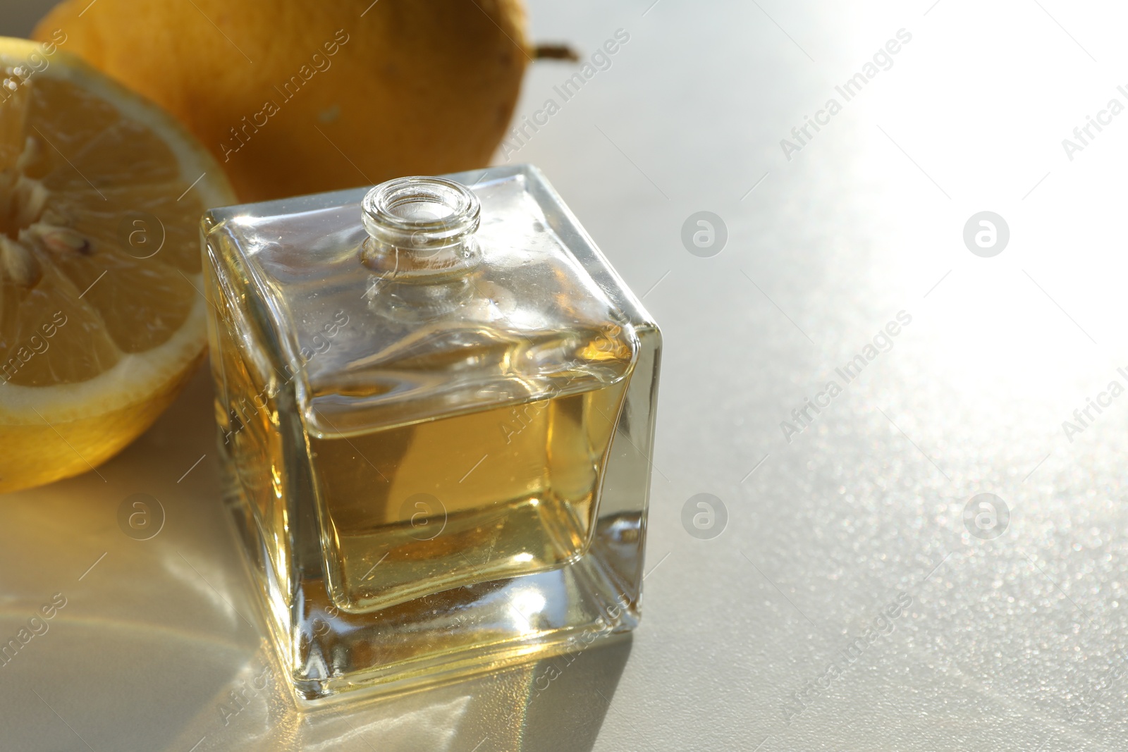 Perfume bottle with aromatic oil and lemons on light background, closeup. Space for text Photo of Perfume bottle with aromatic oil and lemons on light background, closeup. Space for text
