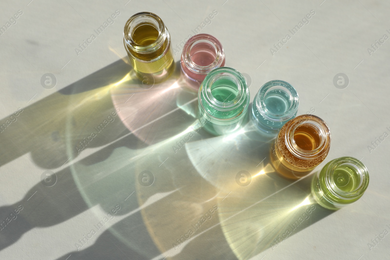 Photo of Perfume bottles with aromatic oils on light background, above view