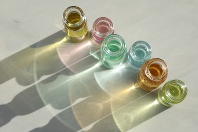 Photo of Perfume bottles with aromatic oils on light background, above view