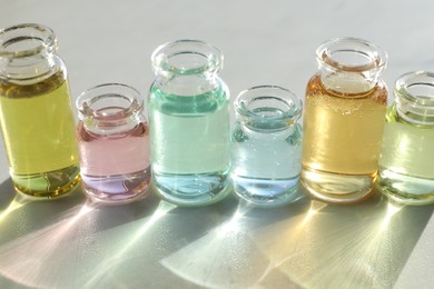 Photo of Perfume bottles with aromatic oils on light background, closeup