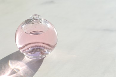 Photo of Perfume bottle with aromatic oil on light background, closeup. Space for text
