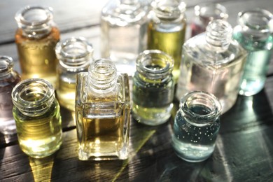 Photo of Perfume bottles with aromatic oils on black wooden background, closeup