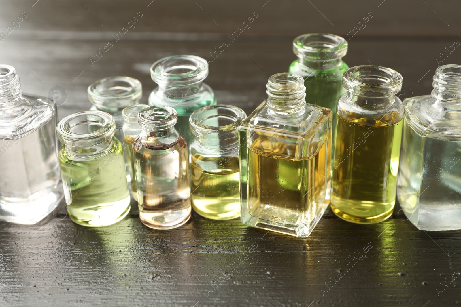 Perfume bottles with aromatic oils on black wooden background, closeup Photo of Perfume bottles with aromatic oils on black wooden background, closeup
