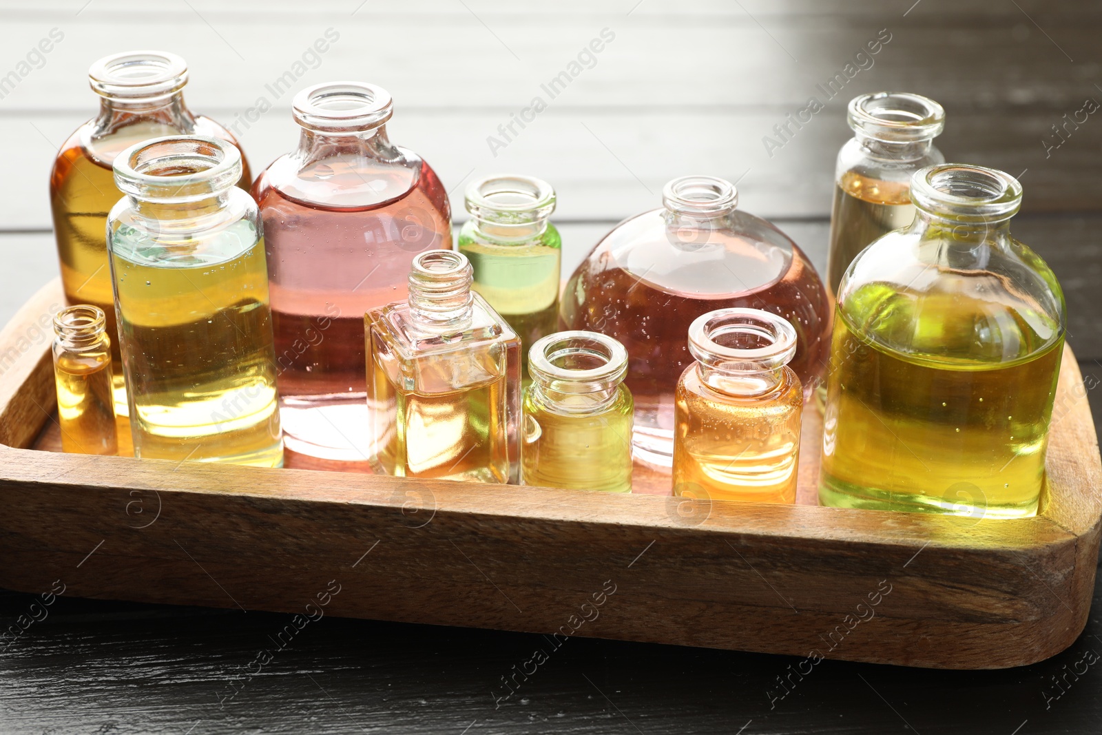 Photo of Perfume bottles with aromatic oils on black wooden background, closeup