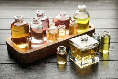 Photo of Perfume bottles with aromatic oils on black wooden background
