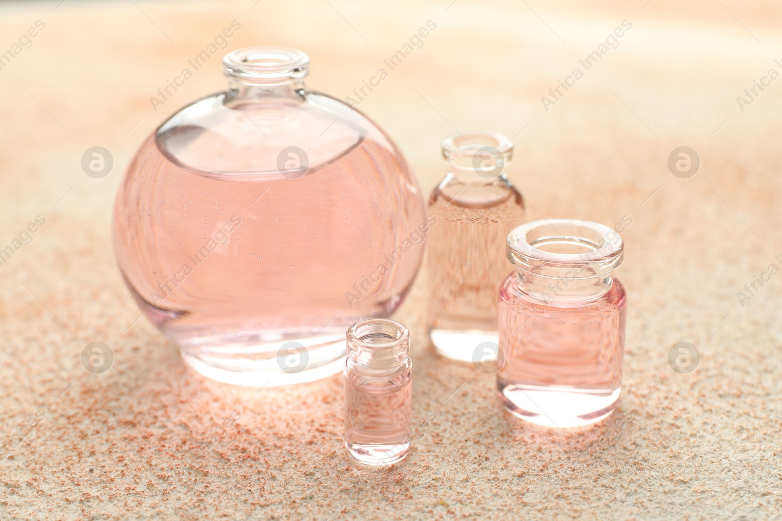 Perfume bottles with aromatic oils on beige textured background, closeup Photo of Perfume bottles with aromatic oils on beige textured background, closeup