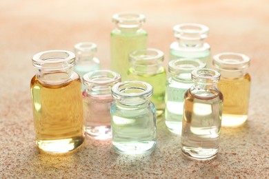Photo of Perfume bottles with aromatic oils on beige textured background, closeup
