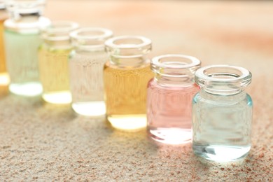 Photo of Perfume bottles with aromatic oils on beige textured background, closeup