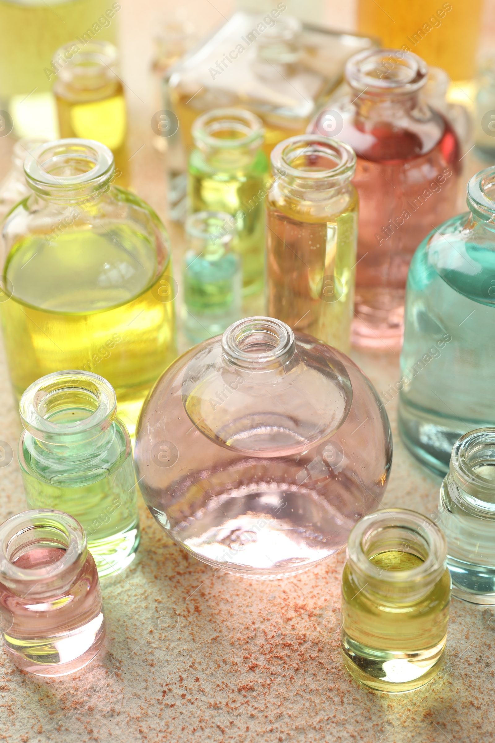 Photo of Perfume bottles with aromatic oils on beige textured background, closeup