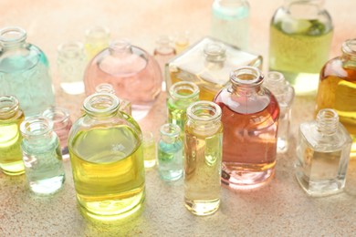 Photo of Perfume bottles with aromatic oils on beige textured background, closeup