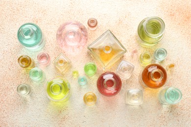 Photo of Perfume bottles with aromatic oils on beige textured background, flat lay