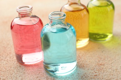 Photo of Perfume bottles with aromatic oils on beige textured background, closeup
