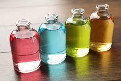 Photo of Perfume bottles with aromatic oils on wooden background, closeup