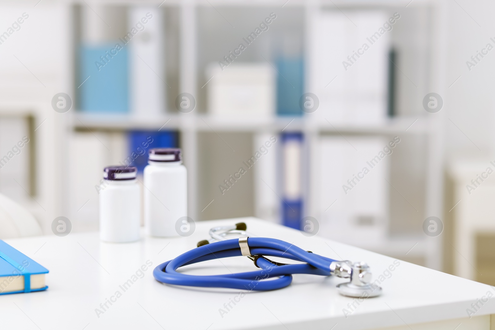 Stethoscope and medical bottles on desk in doctor's office, closeup. Space for text Photo of Stethoscope and medical bottles on desk in doctor's office, closeup. Space for text