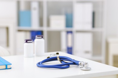 Photo of Stethoscope and medical bottles on desk in doctor's office, closeup. Space for text