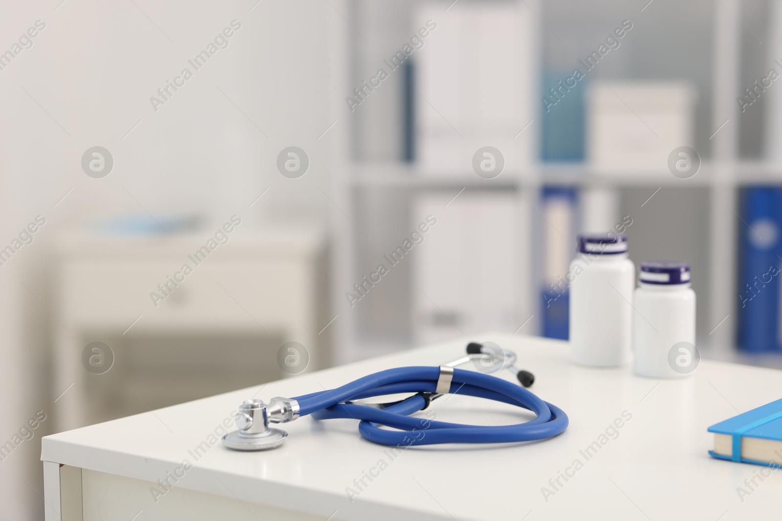 Stethoscope and medical bottles on desk in doctor's office, closeup. Space for text Photo of Stethoscope and medical bottles on desk in doctor's office, closeup. Space for text