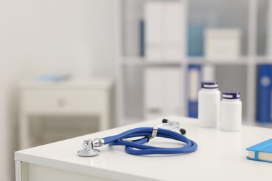 Photo of Stethoscope and medical bottles on desk in doctor's office, closeup. Space for text