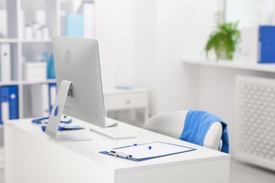 Photo of Doctor's workplace with computer and paperwork on desk. Space for text