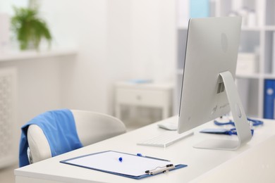 Photo of Doctor's workplace with computer and paperwork on desk. Space for text