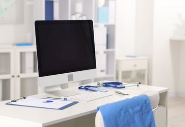 Photo of Doctor's workplace with stethoscope, paperwork and computer on desk