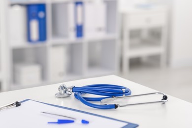 Photo of Doctor's workplace with stethoscope and paperwork on desk, closeup. Space for text