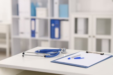 Photo of Doctor's workplace with stethoscope and paperwork on desk, closeup. Space for text