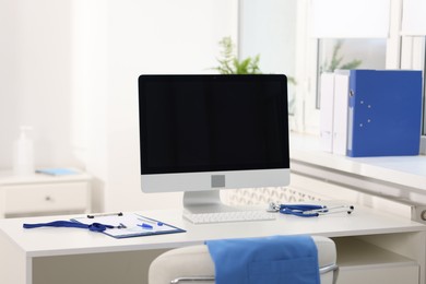 Photo of Doctor's workplace with stethoscope, paperwork and computer on desk