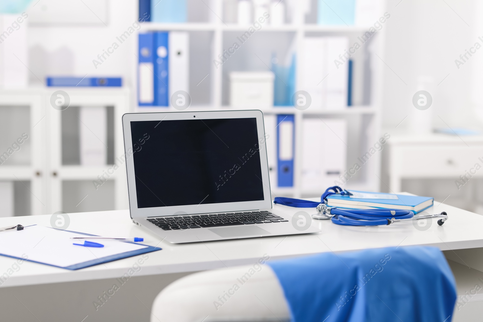Doctor's workplace with stethoscope, paperwork and laptop on desk Photo of Doctor's workplace with stethoscope, paperwork and laptop on desk