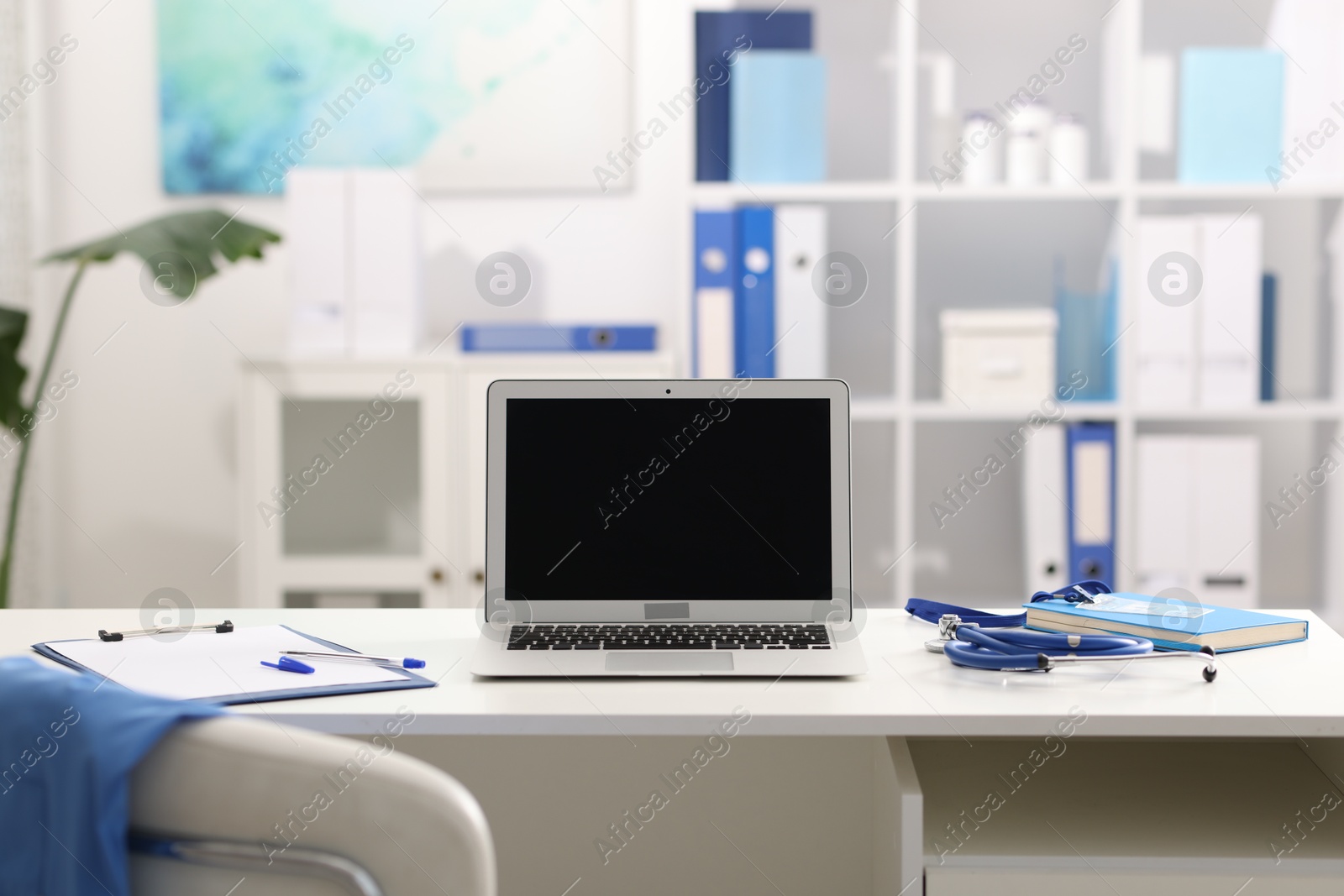 Doctor's workplace with stethoscope, paperwork and laptop on desk Photo of Doctor's workplace with stethoscope, paperwork and laptop on desk